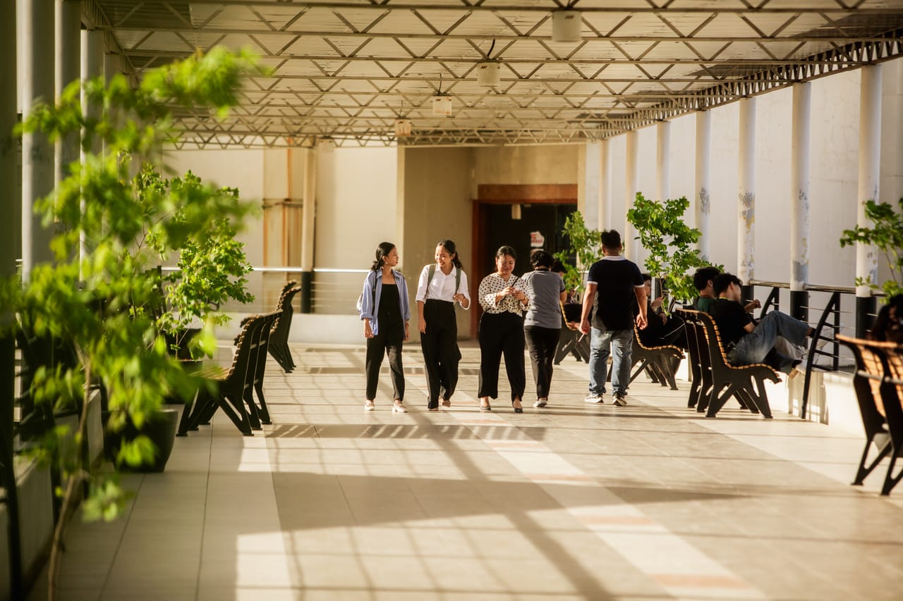 Visitors walk through the sunlit bridge walkway at Limketkai Mall — golden-hour light streaming between columns