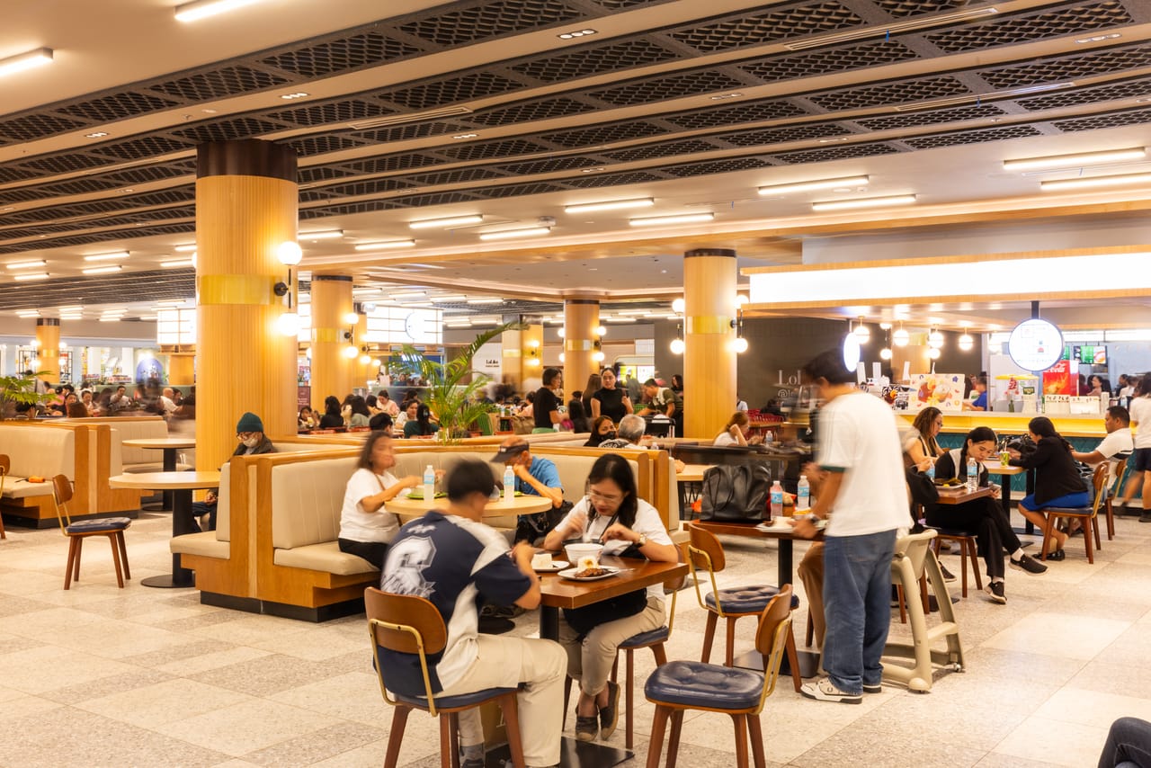 Diners at full tables in Lolika Food Hall, Limketkai Mall — warm evening light along the ground-floor corridor